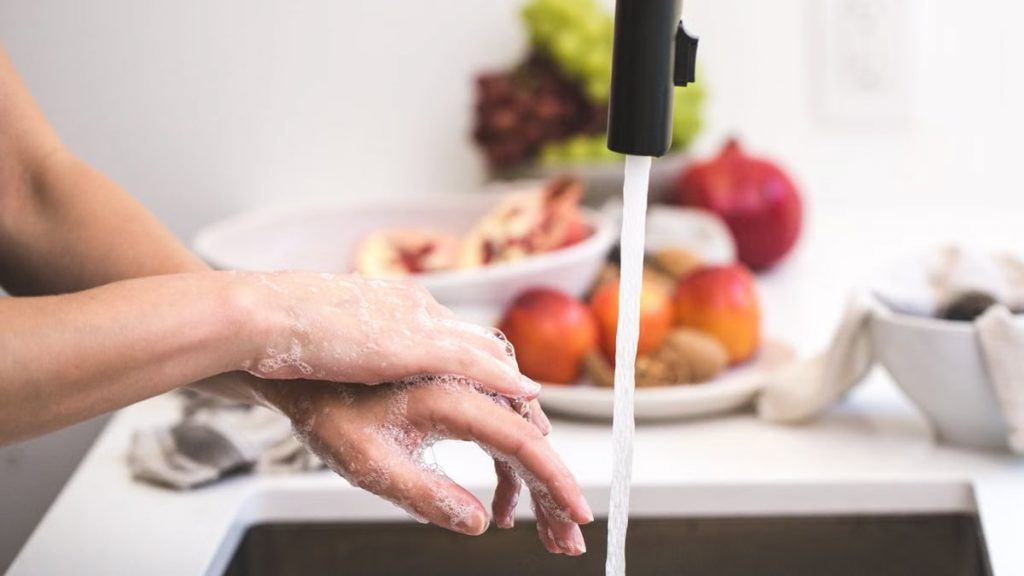Hands washing with soap under faucet, emphasizing cleanliness and hygiene.